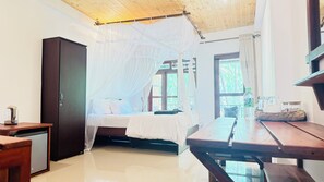 A room with a bed under a canopy, a wooden desk, a small table, and a wardrobe.