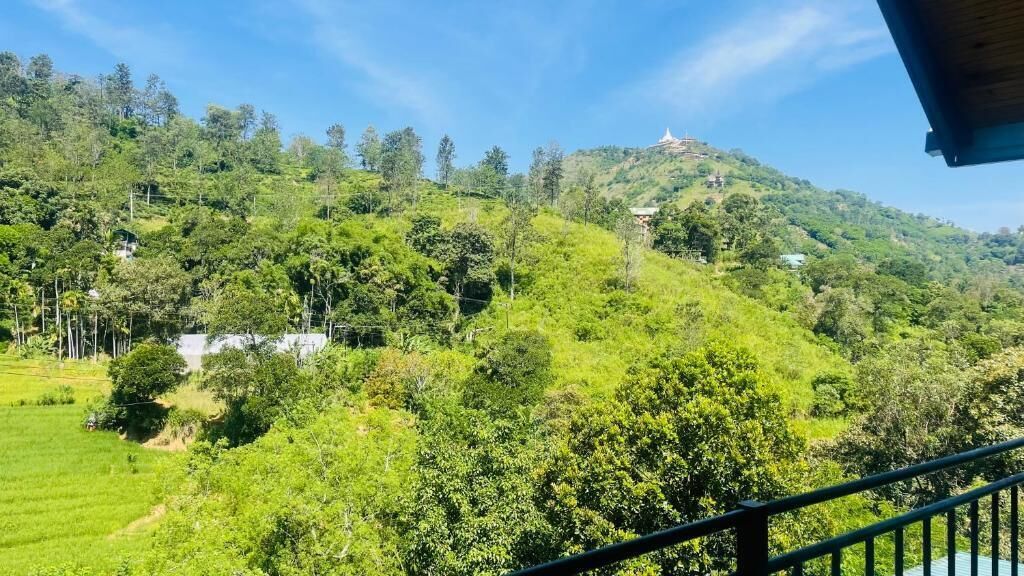 Un paisaje verde y exuberante con una colina, árboles y un edificio en la cima.