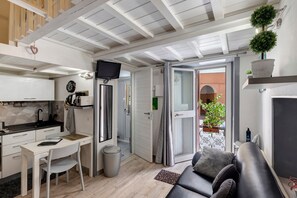 Ein kompakter Wohnbereich mit Küchenzeile, Essbereich, einer Sitzecke mit Sofa und einem kleinen Balkon mit Blumentöpfen.