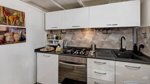 Een moderne keuken met witte kasten, een zwart aanrecht en een geometrisch patroon op de achterwand.