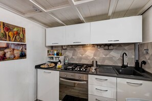 Eine moderne Küche mit weißen Schränken, einer schwarzen Arbeitsplatte und einer geometrischen Spritzschutzwand.