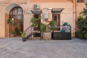 Ein Gebäude mit einer Steinaußenfassade, einer Metalltreppe, Blumentöpfen und Gartenmöbeln.