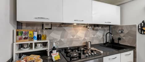 A modern kitchen with white cabinets, a black countertop, and a geometric backsplash.