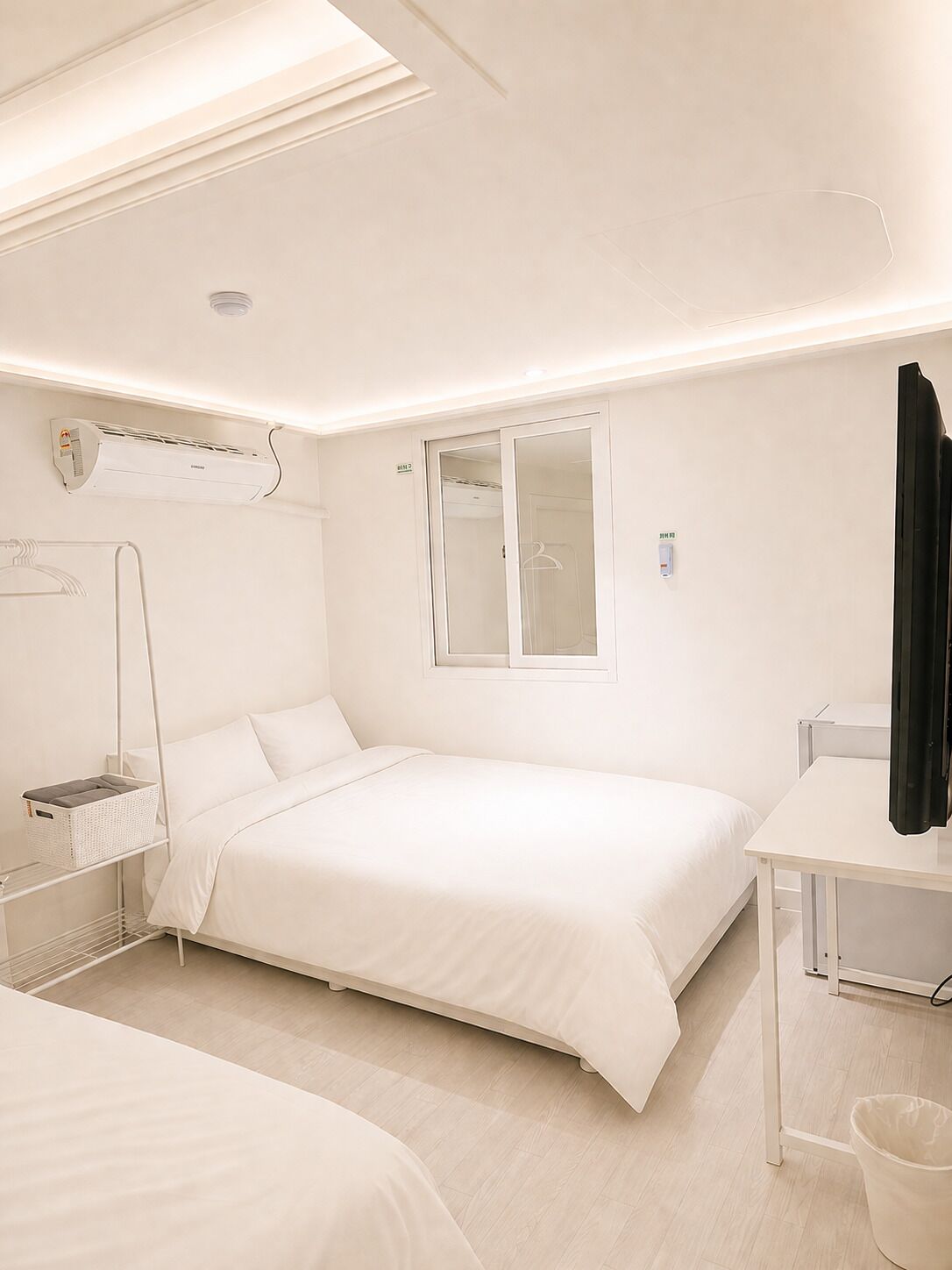 A hotel room with a bed, bedside table, and a window.