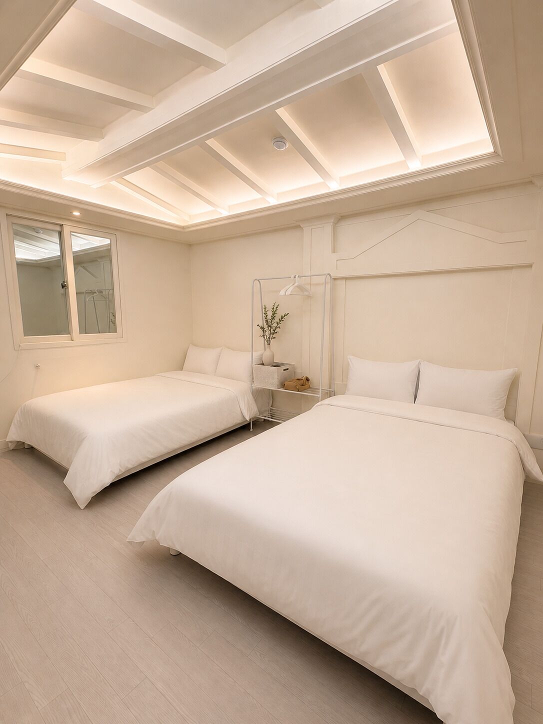 A hotel room with two beds, a window, and a skylight.