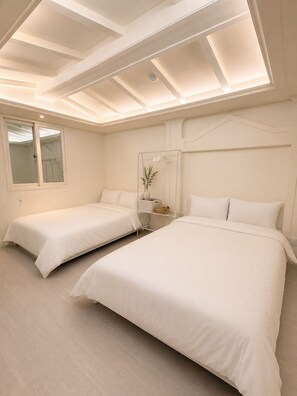 A hotel room with two beds, a window, and a skylight.