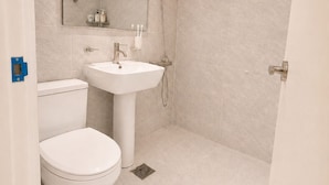 Une salle de bain avec des toilettes, un lavabo et une douche.