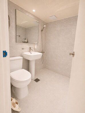 A bathroom with a toilet, sink, and shower.