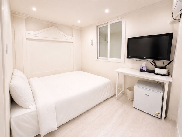 A hotel room with a bed, a television, a desk, and a water dispenser.