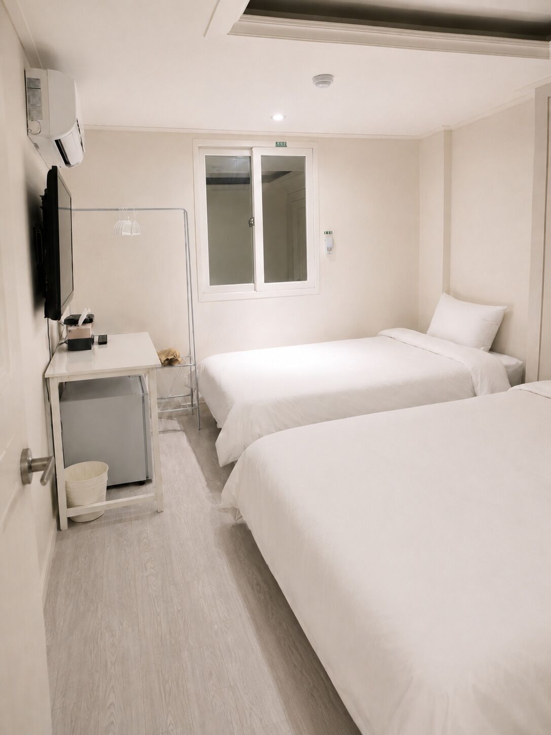Une chambre d’hôtel avec deux lits, une télévision, un bureau avec une chaise et une fenêtre.
