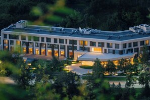 Un edificio moderno con techo plano, múltiples ventanas y un área ajardinada con entrada de acceso curva.