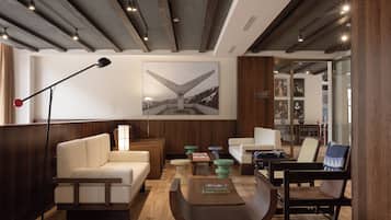 A modern hotel lobby with a sofa, armchair, coffee table, and a floor lamp.