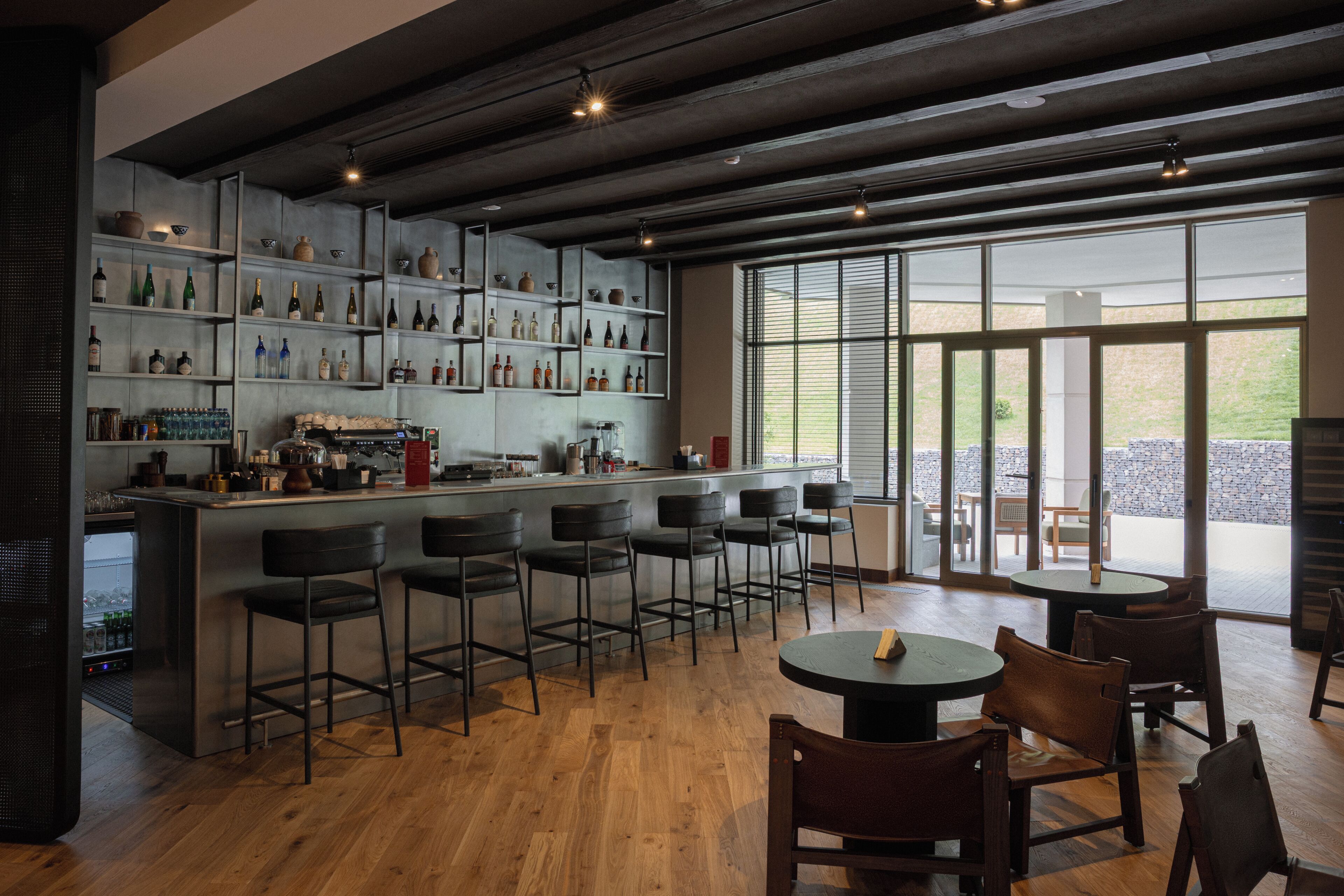 A bar area with multiple shelves of bottles, a coffee machine, and bar stools.