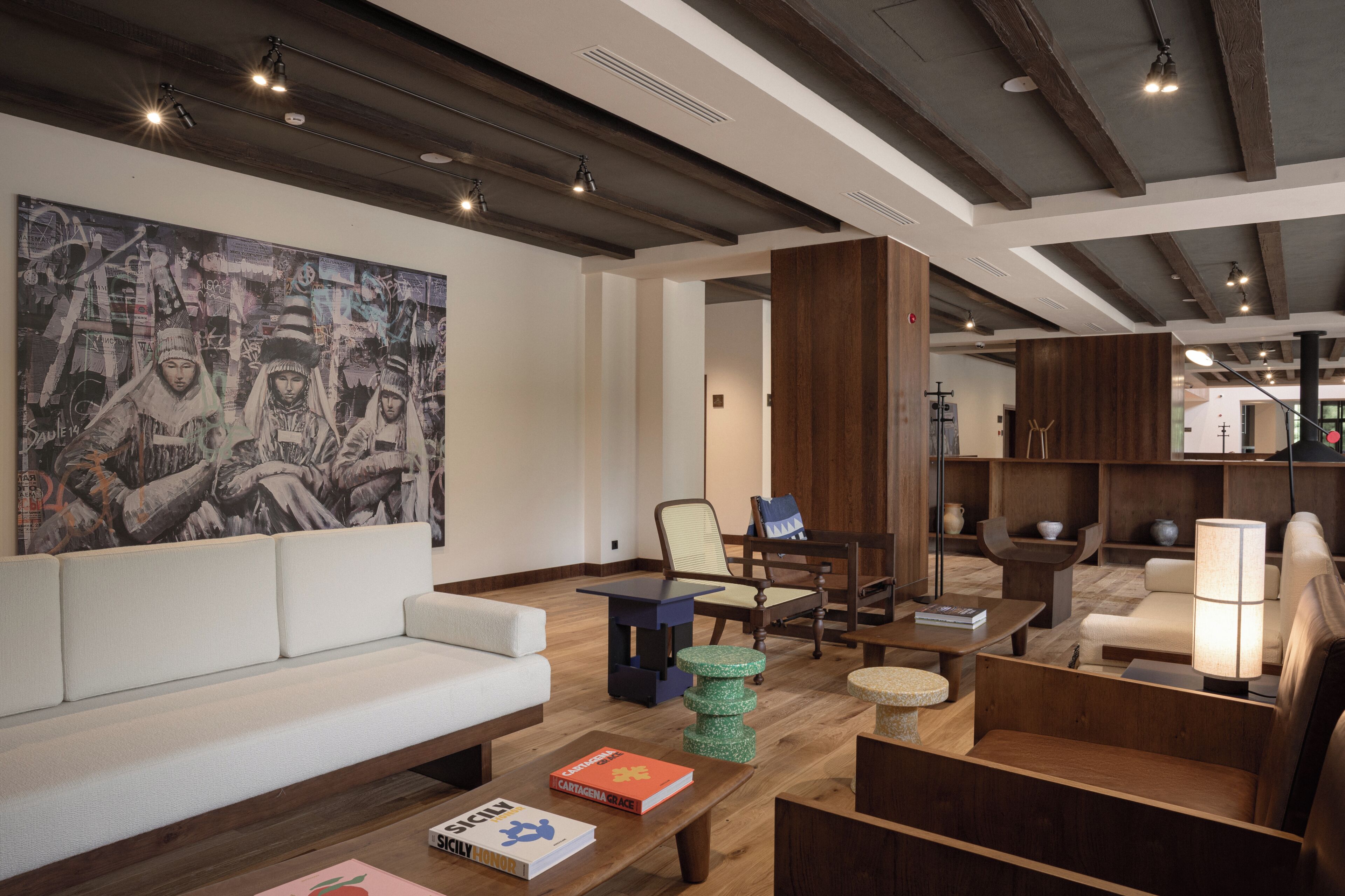 A modern interior with a large abstract painting, wooden furniture, and a mix of seating options.