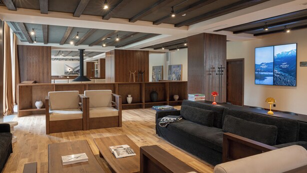 Een moderne woonkamer met houten meubels, een open haard en een grote spiegel.