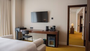 Een hotelkamer met een bed, een bureau, een televisie, een minibar en een koffiezetapparaat.