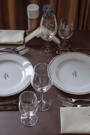 A dining table set with plates, glasses, cutlery, and a napkin. - Medeu Park Hotel (Almaty)