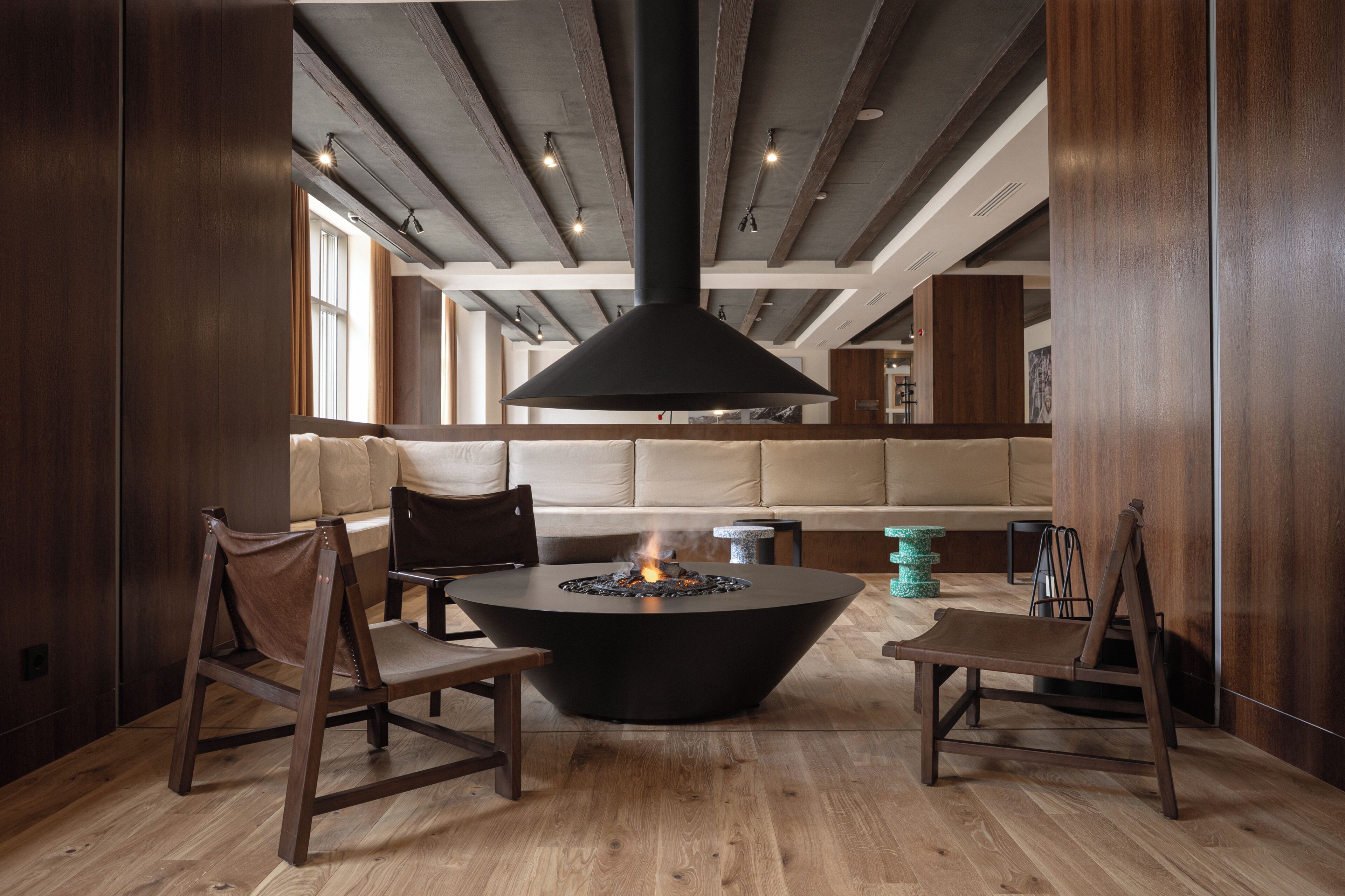 Un interior moderno con una chimenea central, muebles de madera y un techo alto con vigas a la vista.