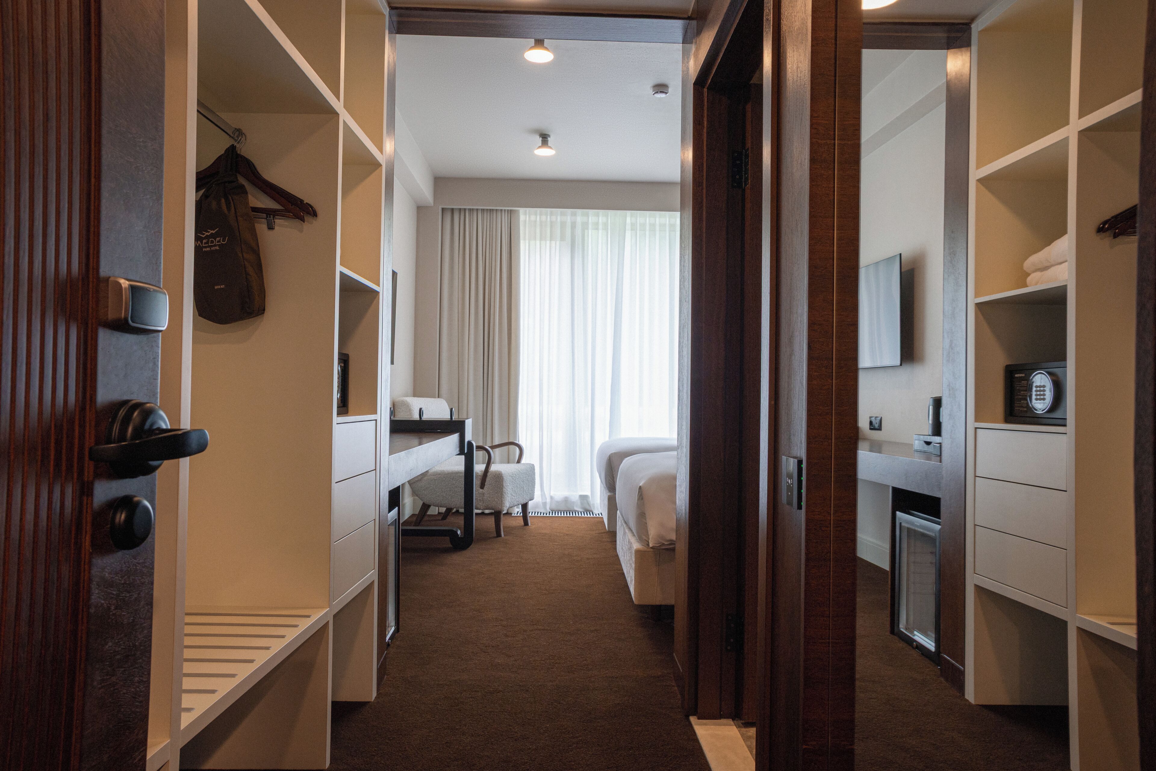 A hotel room with a bed, a desk, a chair, a wardrobe, and a bathroom.