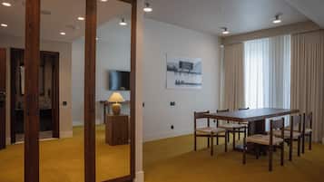 A hotel room with a dining area, a large mirror, a television, and a painting on the wall.