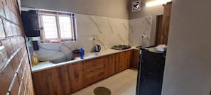 A kitchen with a marble backsplash, wooden cabinets, a sink, a stove, and a window with blinds.