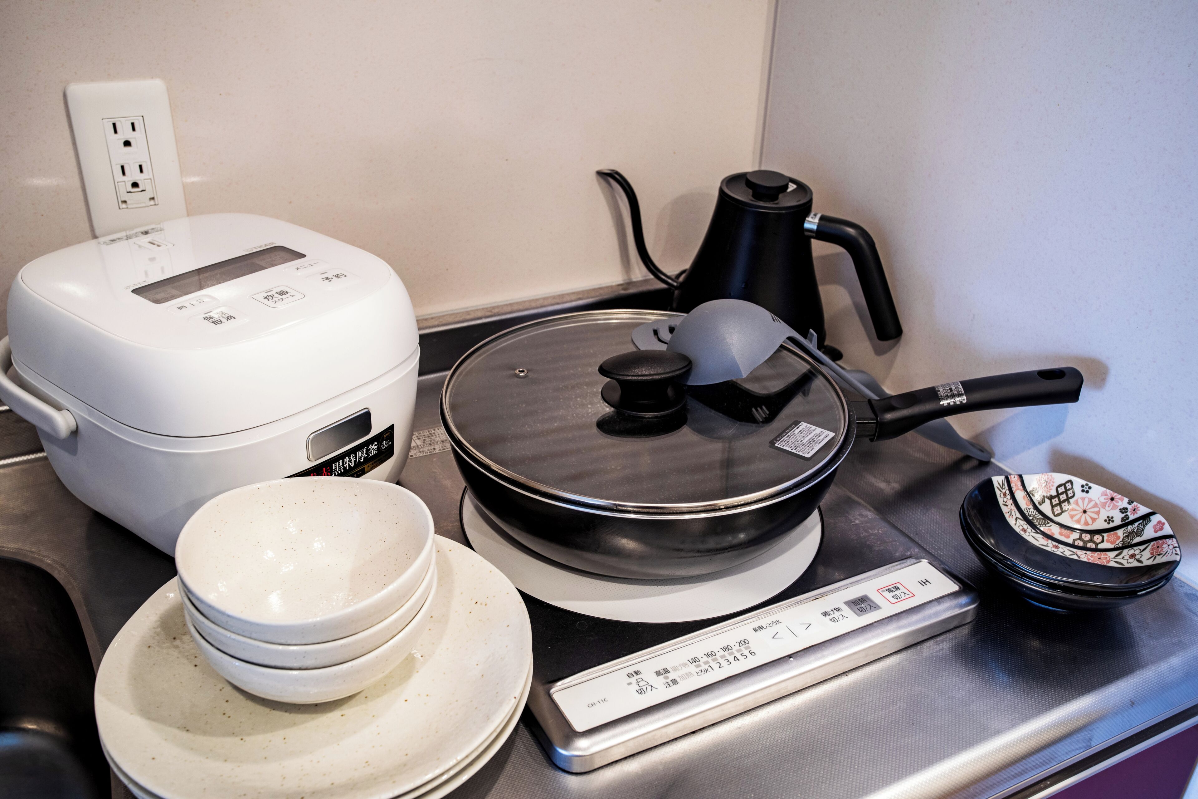 A kitchen with a rice cooker, a pressure cooker, a kettle, and a scale.