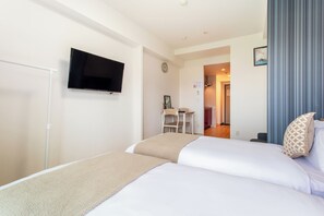 Une chambre d’hôtel comprenant un lit, un téléviseur fixé au mur, un bureau avec une chaise et une porte donnant sur une salle de bain.