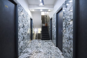 A hallway with marble flooring and walls, leading to a staircase.