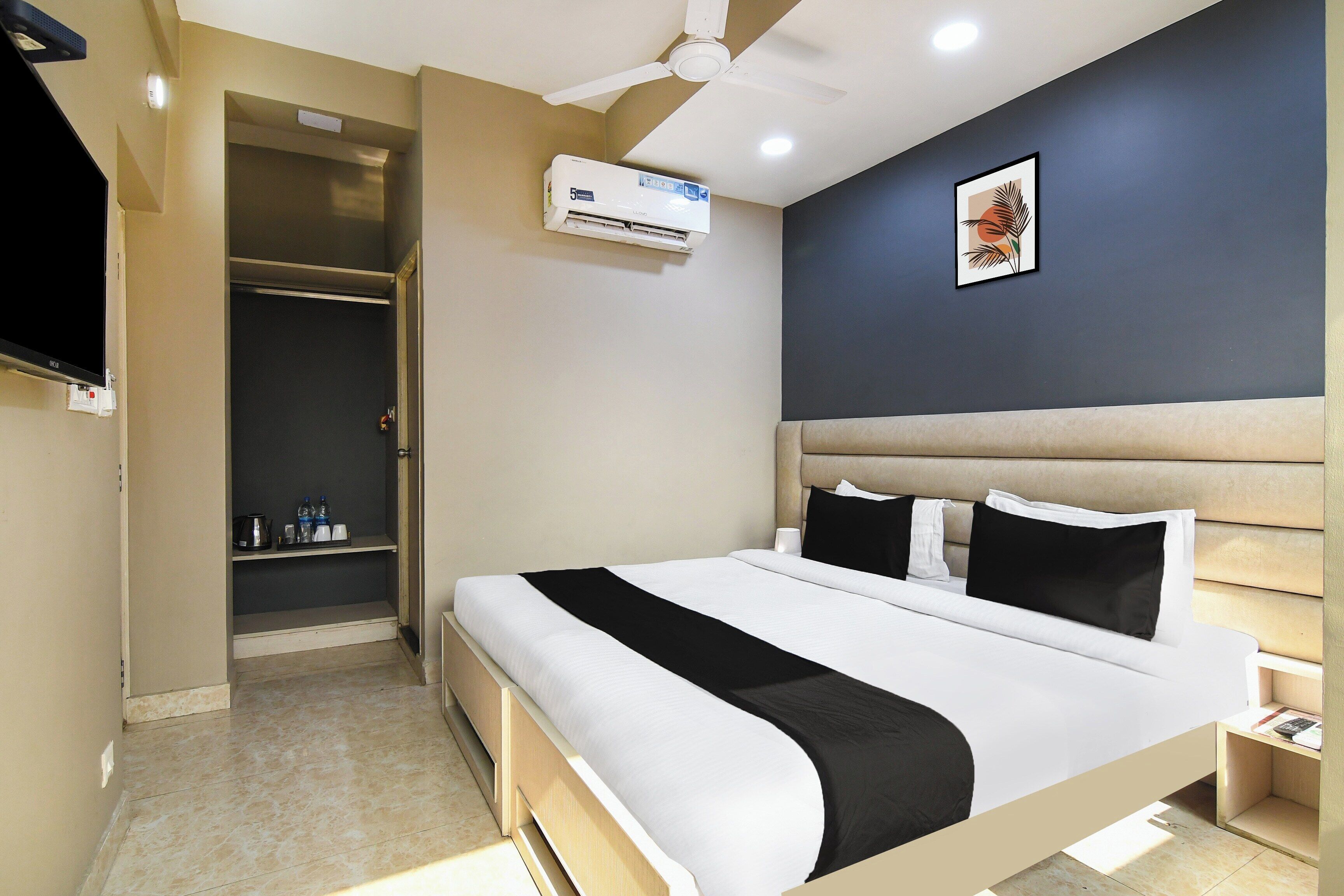 A hotel room with a bed, bedside table, nightstand, and a ceiling fan.