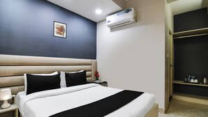 Une chambre d’hôtel équipée d’un lit, d’une table de chevet, d’une lampe, d’un climatiseur et d’un tableau encadré au mur.