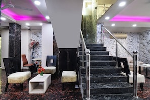 A lobby with a marble staircase, seating area, and a reception desk.