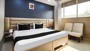 Une chambre d’hôtel avec un grand lit, des tables de chevet, une chaise, une fenêtre avec vue et une œuvre d’art accrochée au mur.