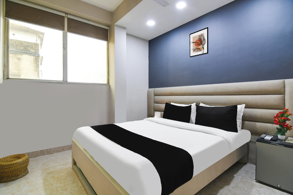 A hotel room with a bed, a nightstand, a wall-mounted picture, and a window.