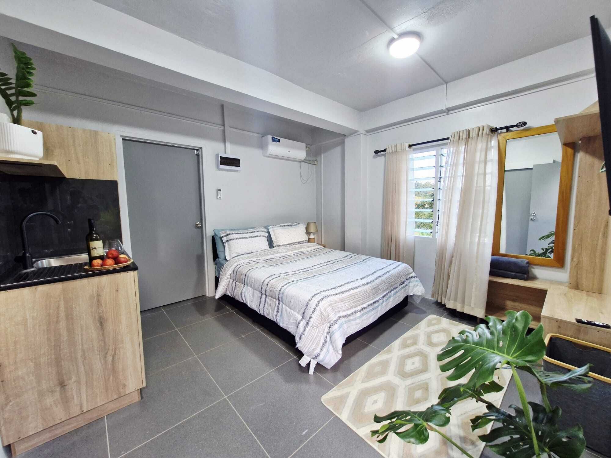 A modern bedroom with a bed, bedside table, and a window with curtains.