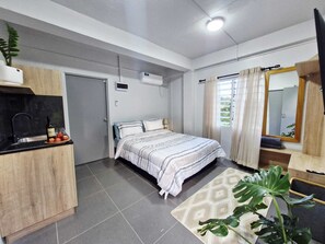 Un dormitorio moderno con cama, mesita de noche y ventana con cortinas.
