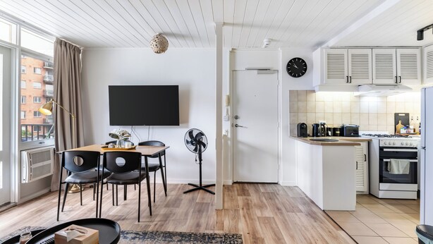 En modern lägenhet med matplats, kök och ett stort fönster.