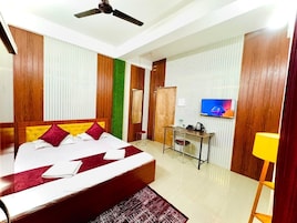 A hotel room with a bed, a desk, a television, and a ceiling fan.