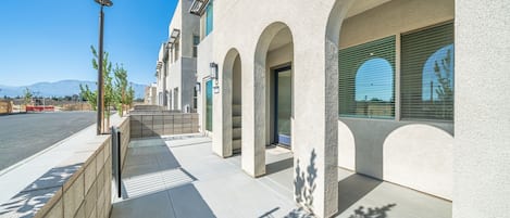 A modern building with a concrete facade, arched doorways, and a clear sky.