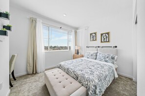 A bedroom with a large bed, a bench, a chair, a nightstand, and a window with curtains. - 20% OFF Luxury 3BR Home, Modern Design & Comfort (Ontario)
