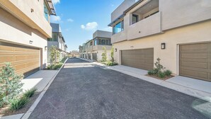 En bostadsgata med moderna hus, garageportar och en klar himmel.