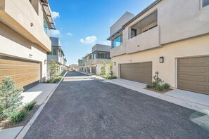 Eine Wohnstraße mit modernen Häusern, Garagentoren und blauem Himmel.