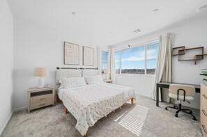 A bedroom with a bed, bedside table, lamp, desk, chair, and a window with curtains. - 20% OFF Luxury 3BR Home, Modern Design & Comfort (Ontario)