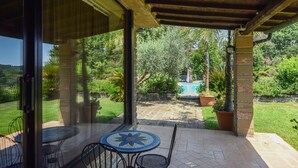 A covered patio with a mosaic table and chairs, a pool, and lush greenery in the background. - Stunning home in Canale Monterano (Canale Monterano)