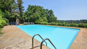 A rectangular swimming pool with a stone deck and metal ladder, surrounded by lush greenery and a clear sky. - Stunning home in Canale Monterano (Canale Monterano)