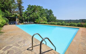 A rectangular swimming pool with a stone deck and metal ladder, surrounded by lush greenery and a clear sky. - Stunning home in Canale Monterano (Canale Monterano)