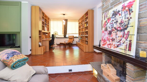 A living room with a fireplace, a sofa, a television, and a bookshelf. - Stunning home in Canale Monterano (Canale Monterano)