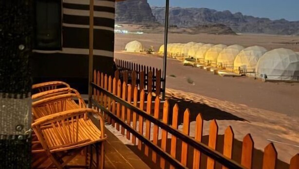 Un balcón con sillas de madera y vistas de yurtas en un paisaje desértico.