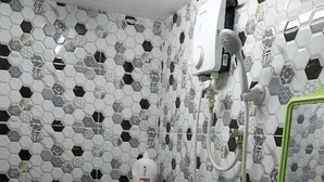 A bathroom with a hexagonal tile pattern, a toilet, a bidet, and a green shelf. - JSW PRAMLee (George Town)