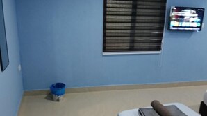A room with a bed, a television mounted on the wall, and a window with blinds. - JSW PRAMLee (George Town)
