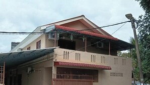 A two-story building with a flat roof, a covered porch, and a fenced front yard. - JSW PRAMLee (George Town)